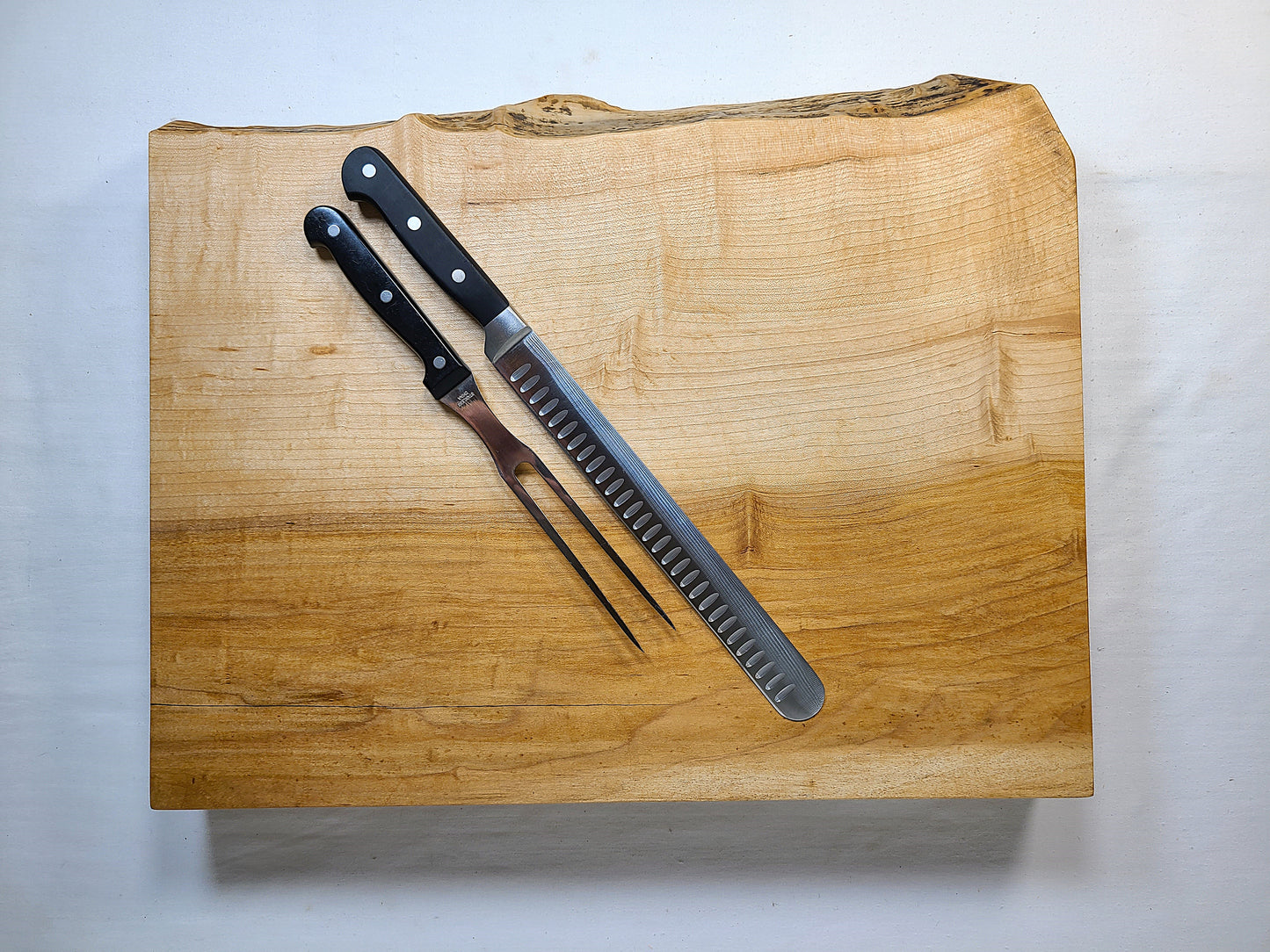 top view of live edge cutting board with a carving knife and meat fork on top