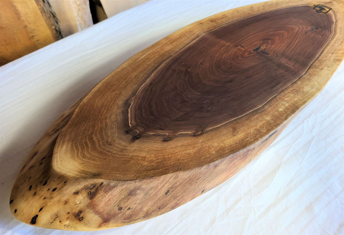 Large oval wood charcuterie board made of walnut. You can see the rings of the tree from the dark center to the light edge. Custom serving board made in USA