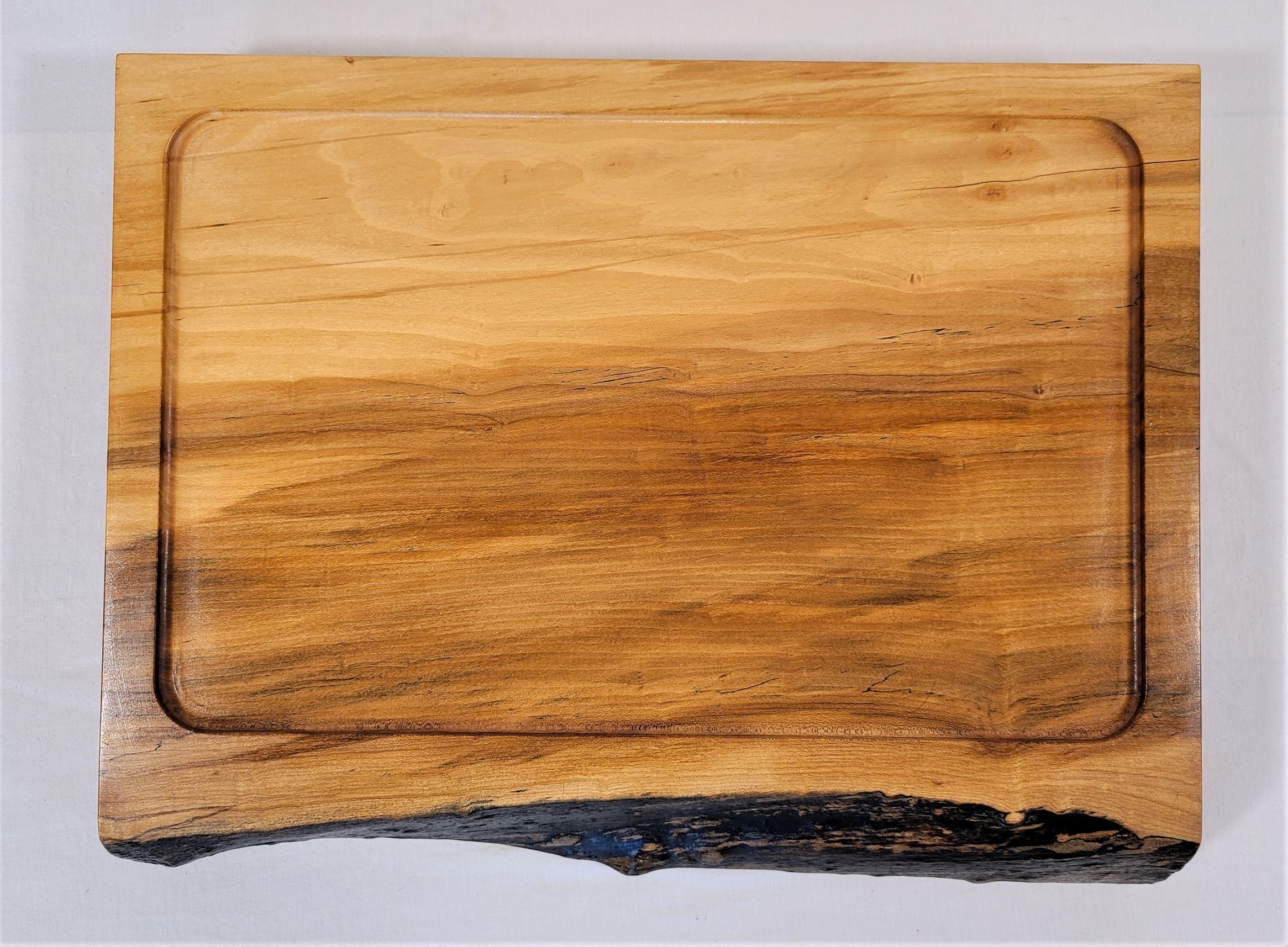 Top view of a custom made large cutting board.  Made of a thick piece of maple this carving board can handle large meat and poultry and catch all drippings in the extra large scooped out well.  Made in USA by ZIM Boards