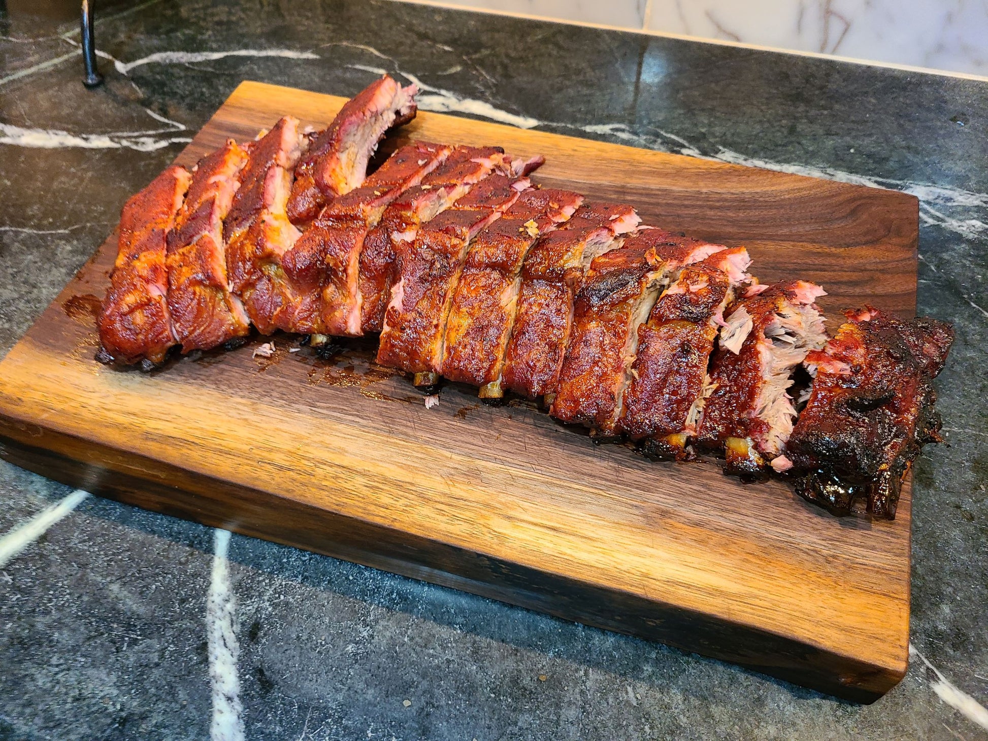 full rack of ribs on a large carving board made of walnut