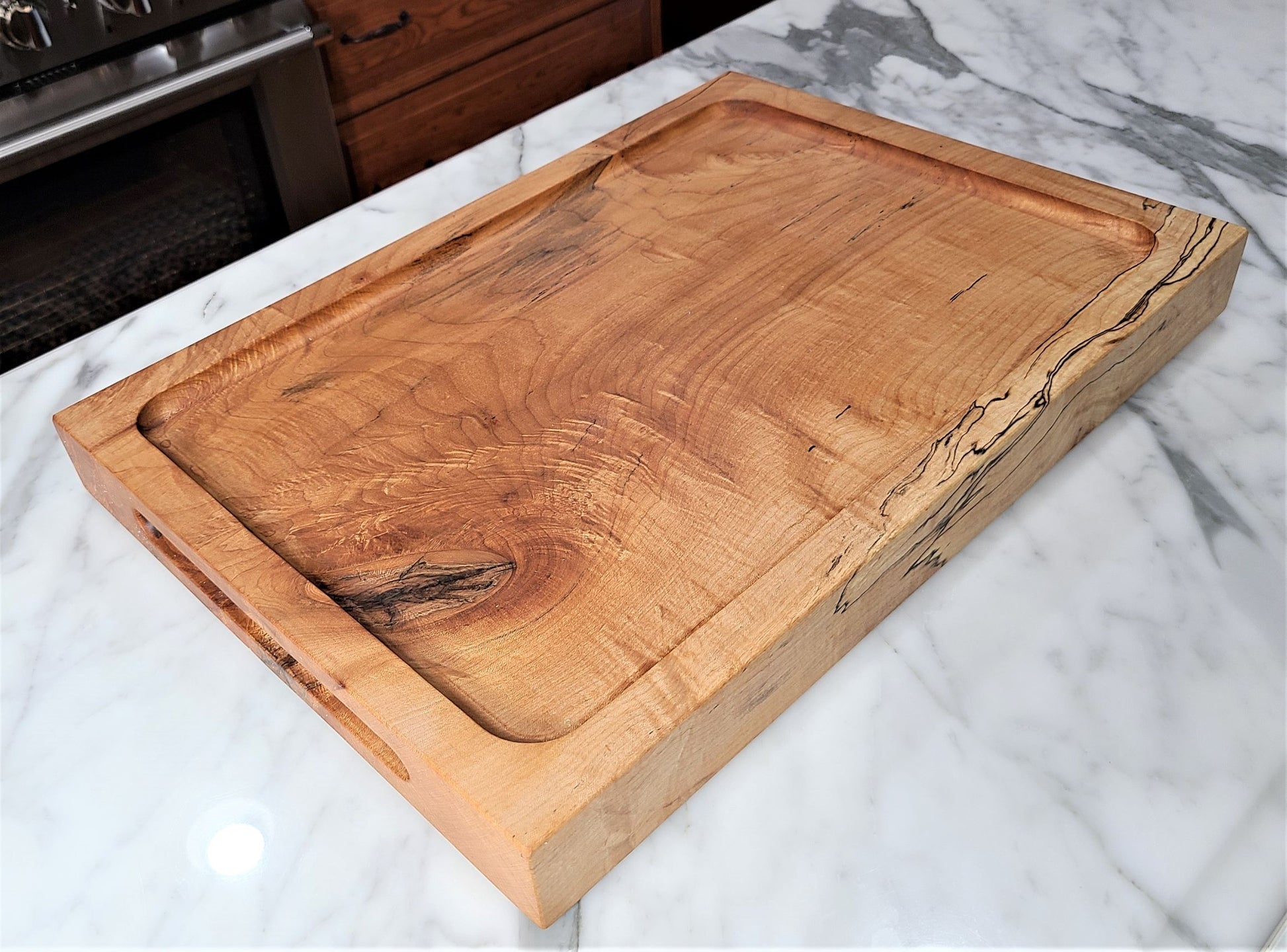 Beautiful high end custom large cutting board made of a solid piece of 2 inch thick maple. Carving  board on one side features a deep well to capture juices from meat or poultry.  Reverses to a flat top cutting board .  Made in USA by ZIM Boards.