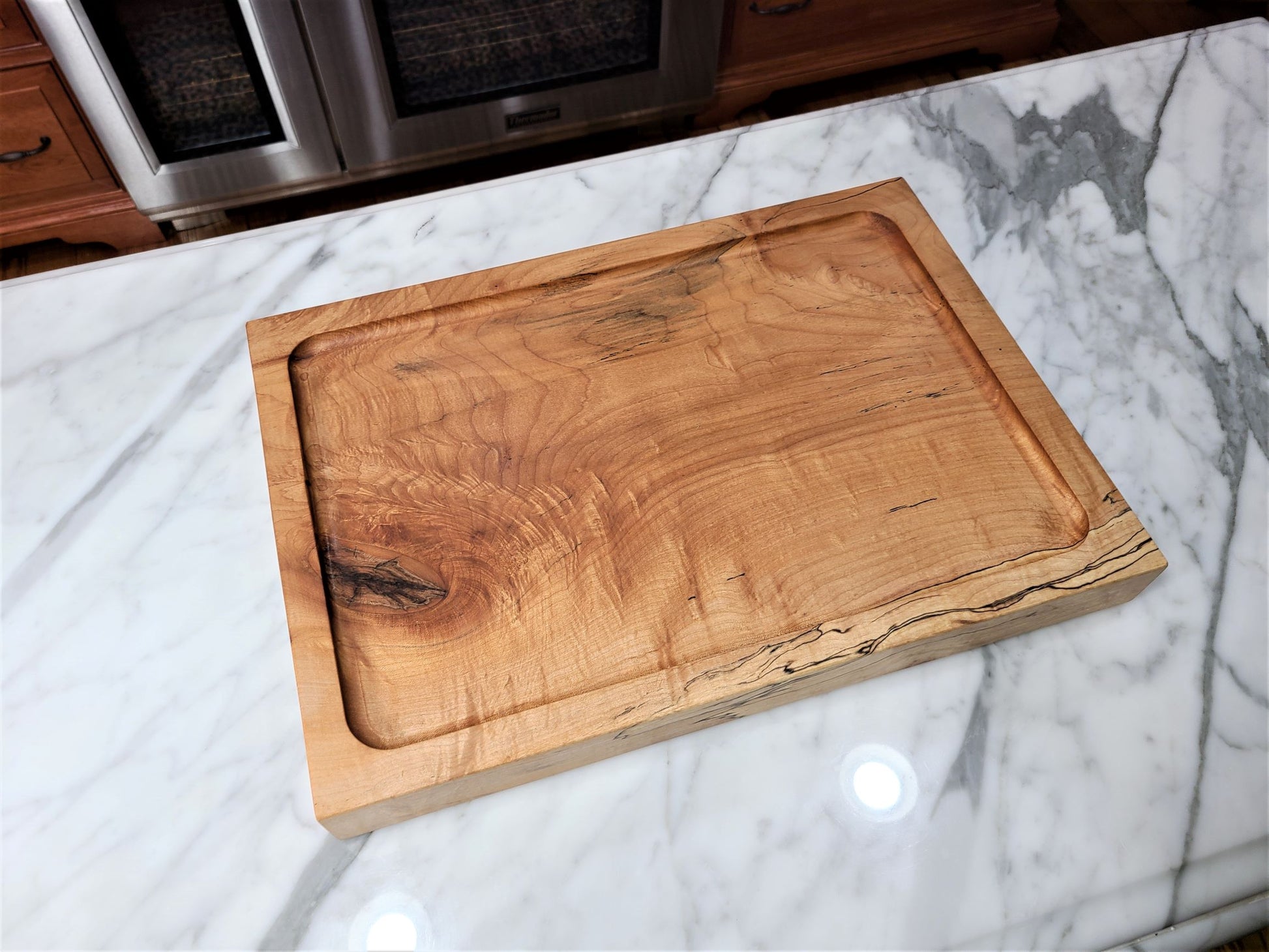 Top view of a custom made large wood carving board.  Made of a thick piece of Maple and reverses to a flat top maple cutting board with a live edge.  Made in USA by ZIM Boards