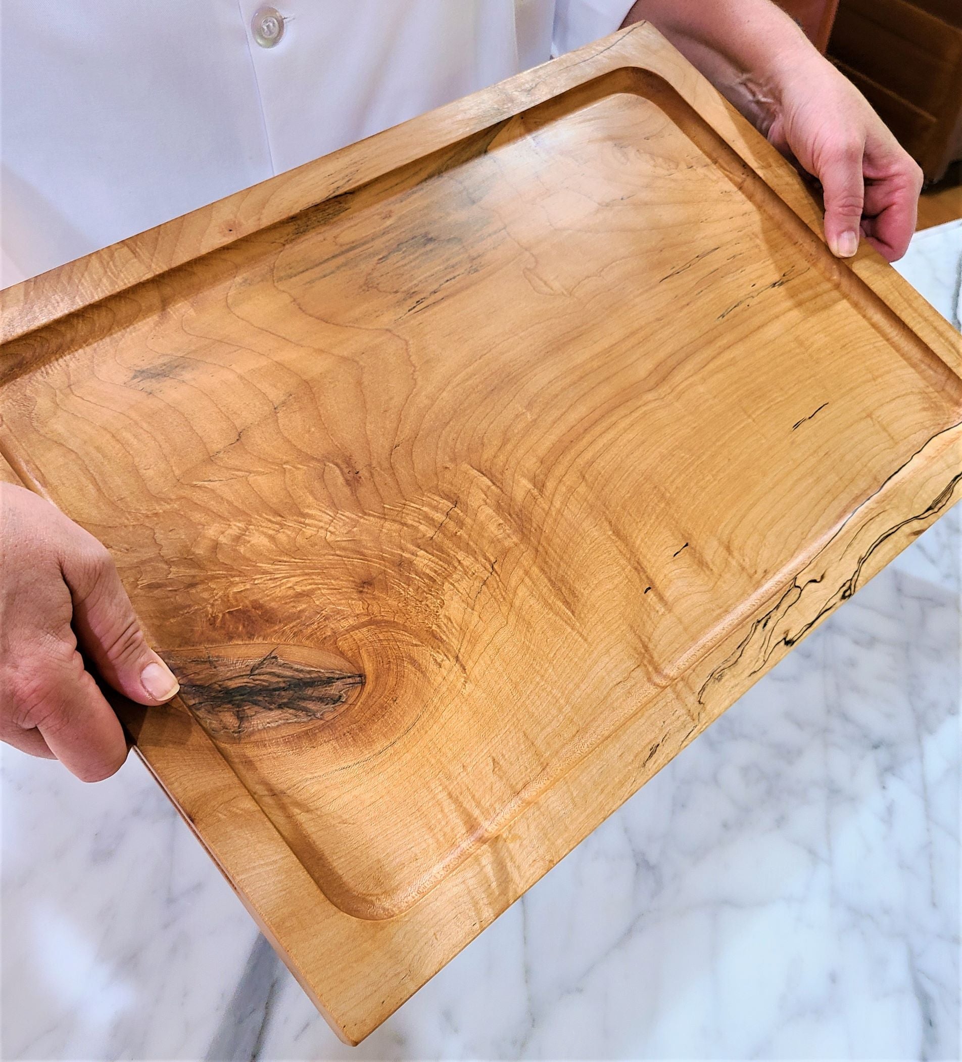 Person holding a custom made large cutting, carving board. Made of a solid piece of Maple 2 inch thick.  Can be personalized. Made in USA by ZIM Boards.
